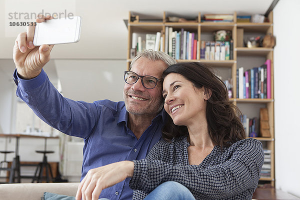 Lächelndes Paar zu Hause mit einem Selfie