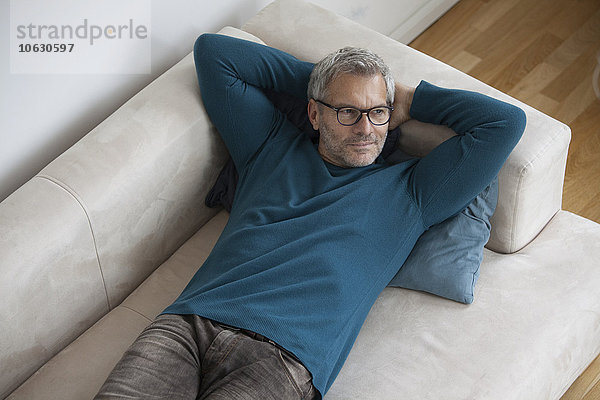 Entspannter reifer Mann zu Hause auf der Couch liegend
