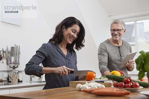 Reife Paare mit digitalem Tablettenkochen in der Küche
