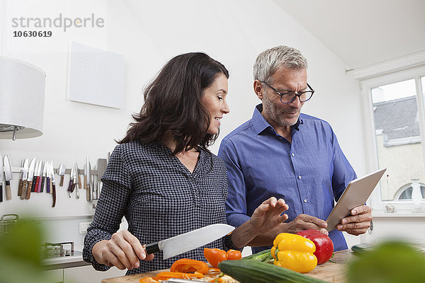 Reife Paare mit digitalem Tablettenkochen in der Küche