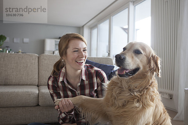 Porträt der lächelnden jungen Frau mit der Pfote ihres Hundes