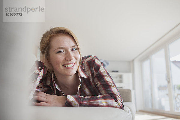Porträt einer lächelnden jungen Frau auf der Couch zu Hause