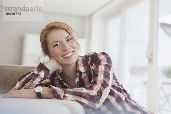 Porträt einer lächelnden jungen Frau  die sich zu Hause entspannt