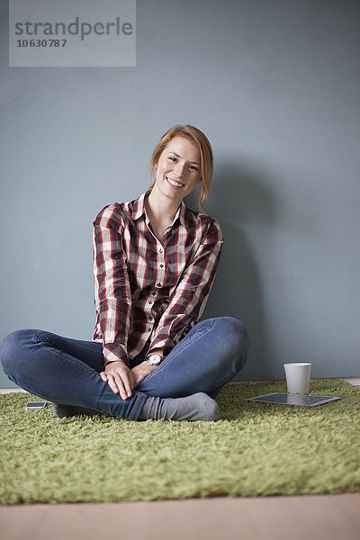 Porträt einer lächelnden jungen Frau auf dem Boden sitzend