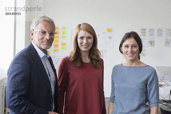 Porträt des lächelnden Geschäftsmannes und zweier Frauen im Amt