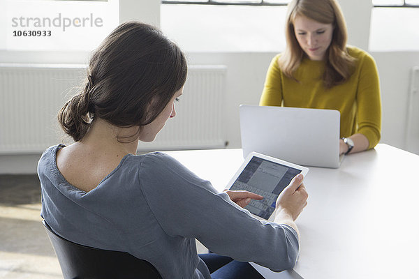 Zwei Frauen im Konferenzraum mit digitalem Tablett und Laptop