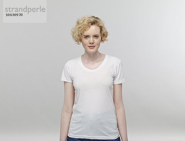 Porträt einer blonden Frau mit weißem T-Shirt vor grauem Hintergrund