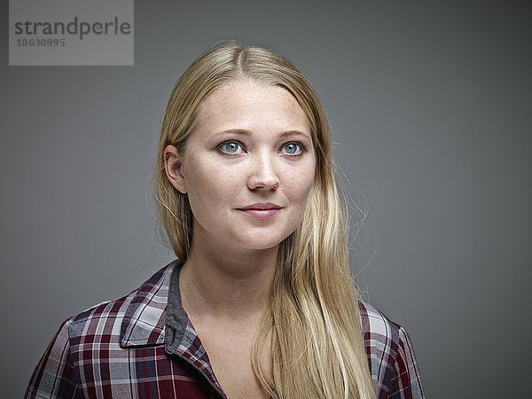 Porträt einer jungen blonden Frau vor grauem Hintergrund