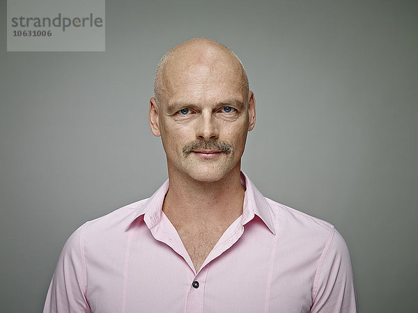 Porträt eines kahlen Mannes mit Schnurrbart im rosa Hemd