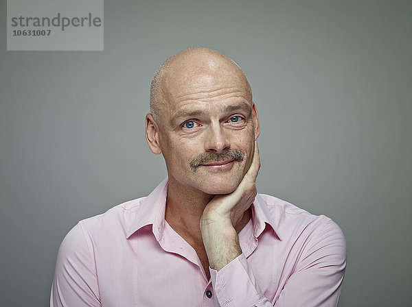Porträt eines kahlen Mannes mit Schnurrbart im rosa Hemd