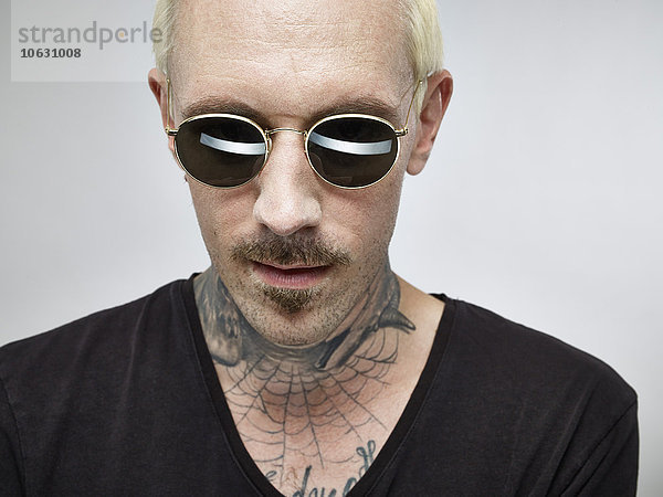 Porträt eines Mannes mit Tattoo und blond gefärbtem Haar mit Sonnenbrille