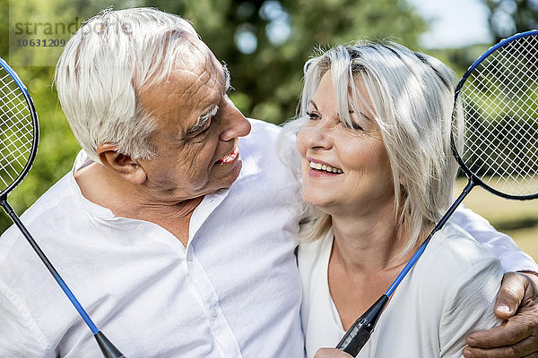 Lächelndes älteres Paar mit Badmintonschlägern im Freien