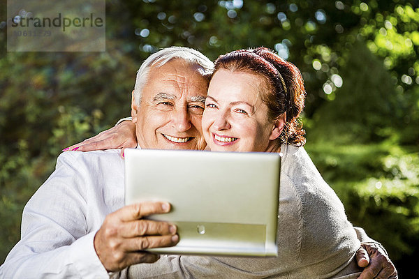 Glückliches älteres Paar mit digitalem Tablett im Freien