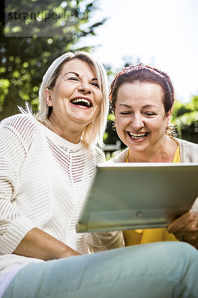 Glückliche reife Frauen im Garten mit digitalem Tablett
