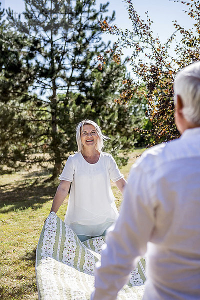 Älteres Paar mit Picknickdecke auf einer Wiese