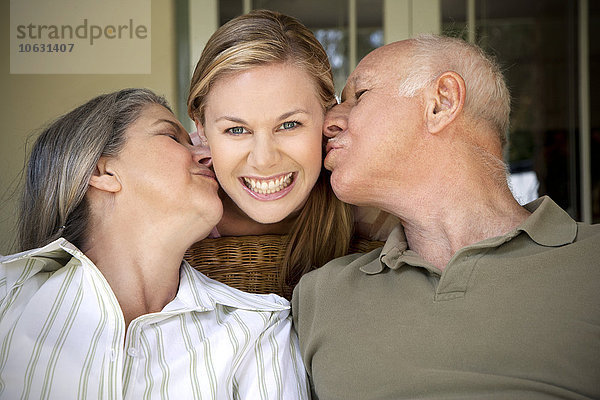 Porträt einer lächelnden Frau mit küssenden Eltern
