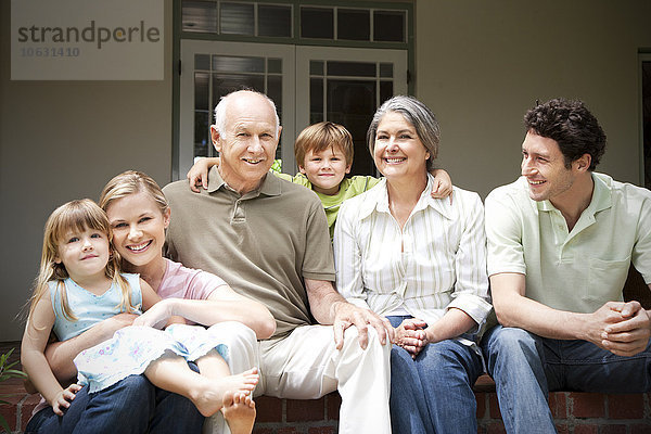 Gruppenbild von drei Generationen Familie auf der Terrasse sitzend