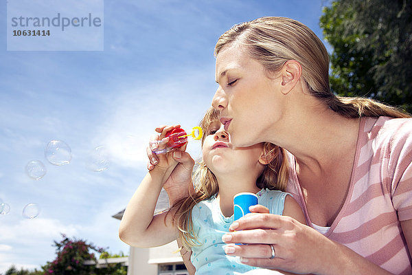 Frau und ihre kleine Tochter bläst Seifenblasen