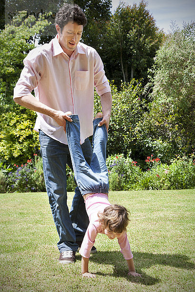 Mann spielt mit seiner kleinen Tochter im Garten