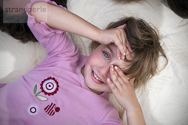 Kleines Mädchen auf Decke liegend  ein Auge mit der Hand bedeckend
