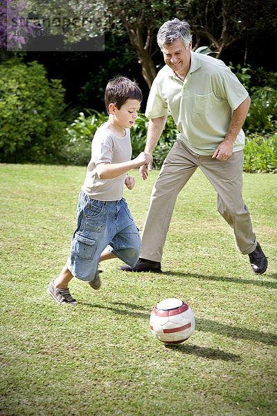 Kleiner Junge spielt Fußball mit seinem Großvater