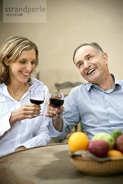 Zwei Freunde stoßen mit Rotwein an.