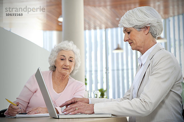 Zwei ältere Frauen arbeiten zusammen am Laptop