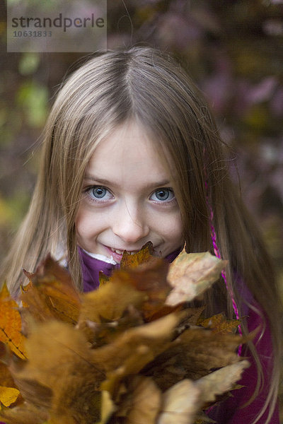 Porträt eines Mädchens mit einem Haufen Herbstblätter