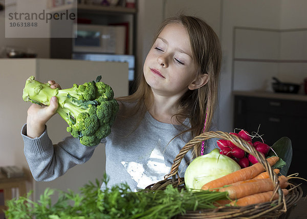 Porträt eines Mädchens mit einem Korb mit frischem Gemüse  das auf Brokkoli blickt