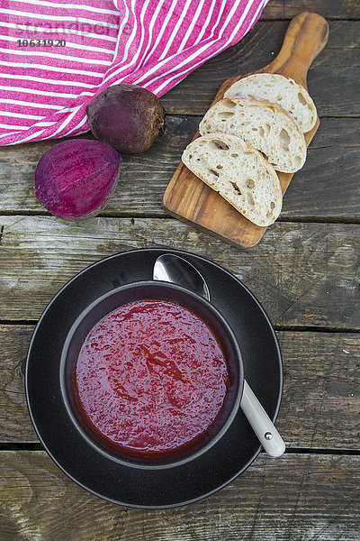 Schüssel mit Rote-Beete-Suppe  Weißbrot auf Hackbrett