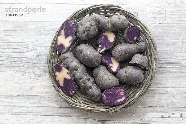 Geschnittene und ganze violette Kartoffeln im runden Korb