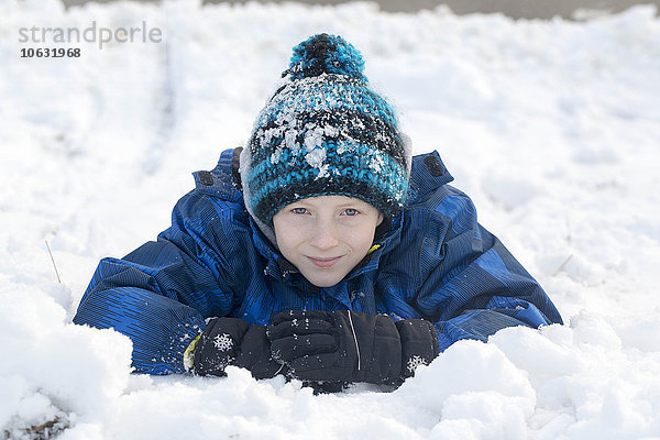Porträt des lächelnden Jungen mit Pudelmütze im Schnee