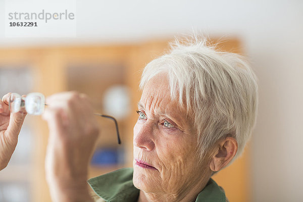 Porträt einer weißhaarigen Seniorin mit Blick auf ihre Brille