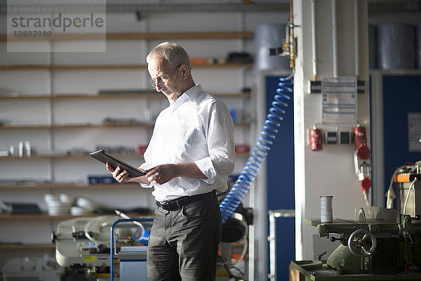 Mann mit digitalem Tablett in einer Werkstatt