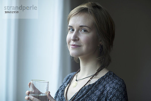 Porträt einer lächelnden jungen Frau mit Wasserglas