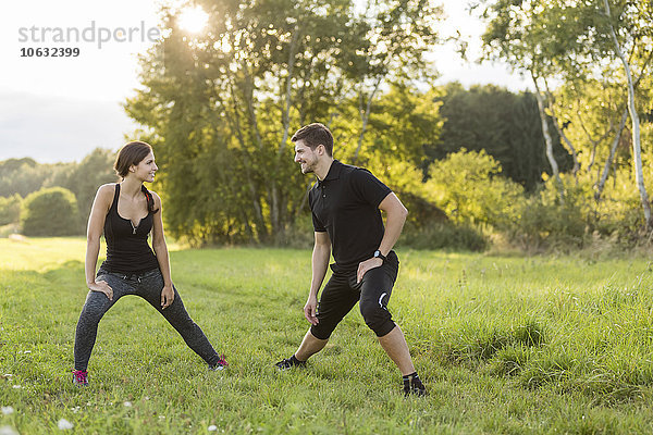 Mann und Frau beim Stretching im Feld