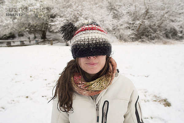 Junge Frau im Winter mit Wollmütze über den Augen