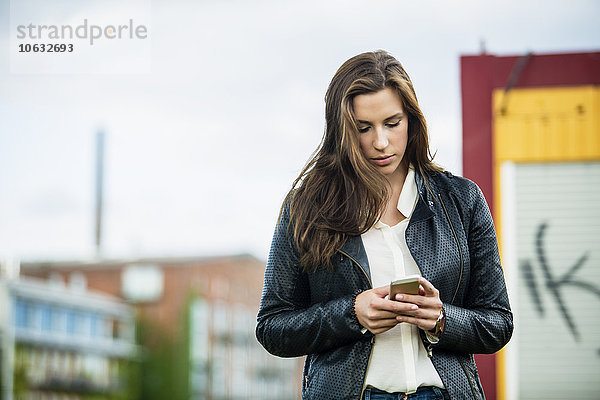 Deutschland  Münster  junge Frau beim Blick auf ihr Smartphone