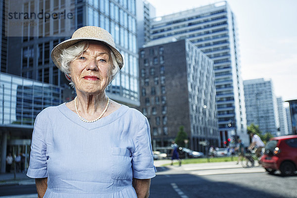 Deutschland  Berlin  Porträt der lächelnden Seniorin mit Hut und Sommerkleid