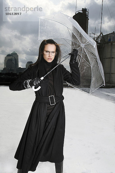 Deutschland  München  Porträt einer Frau in schwarzer Kleidung auf einem Dach mit transparentem Regenschirm