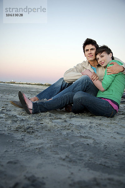 Junges Paar umarmt sich am Strand