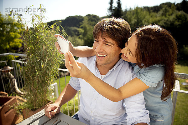 Glückliches Paar auf dem Balkon mit einem Selfie