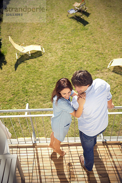 Glückliches Paar steht auf dem Balkon über dem Garten