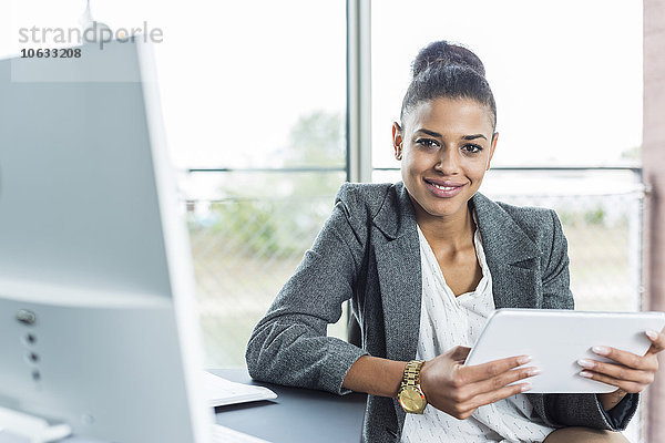 Porträt einer lächelnden jungen Frau im Büro mit digitalem Tablett