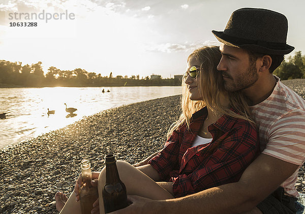 Junges Paar entspannt sich bei Sonnenuntergang am Flussufer