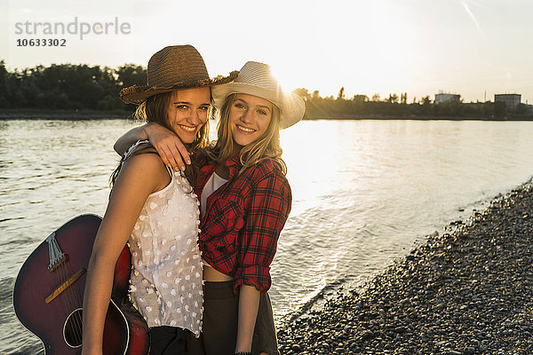 Zwei Freunde  die sich bei Sonnenuntergang am Flussufer umarmen.
