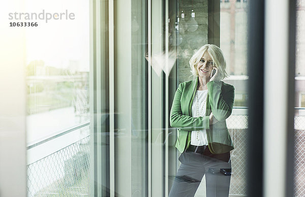 Portrait der blonden Geschäftsfrau beim Telefonieren mit dem Smartphone