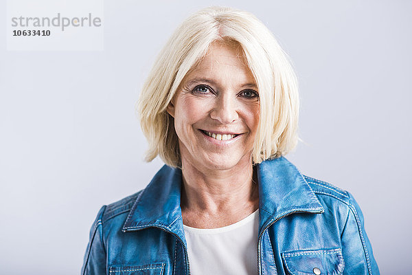 Porträt einer lächelnden blonden Frau mit blauer Lederjacke