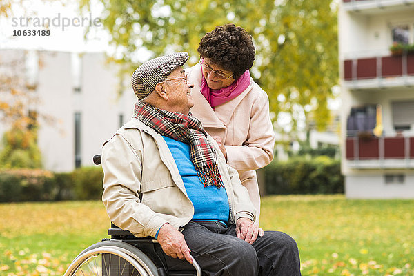 Seniorenfrau sieht Mann im Rollstuhl an
