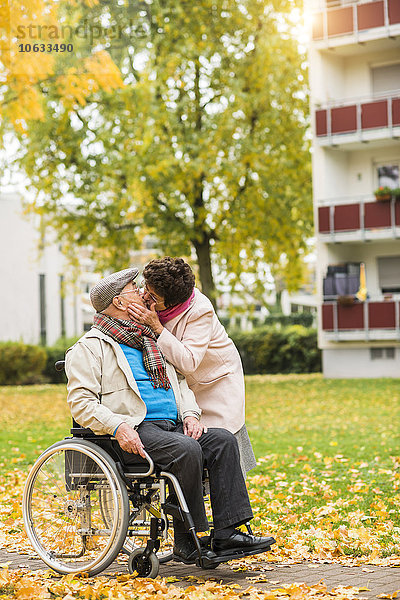 Seniorin küssend Ehemann im Rollstuhl